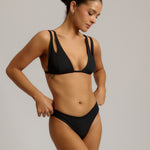 Woman wearing a black bikini against a neutral background