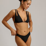 Woman wearing a black bikini against a neutral background