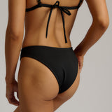 Person wearing a black bikini bottom against a neutral background