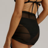 Black bikini with a tied sarong on a neutral background