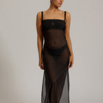 Woman wearing a black sheer dress against a plain background