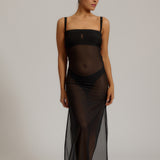 Woman wearing a black sheer dress against a plain background