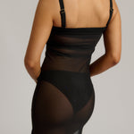 Woman wearing a black sheer dress against a plain background