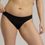 Person wearing a black bikini bottom against a neutral background