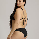 Woman wearing a black bikini with a plain background
