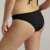 Person wearing a black bikini bottom against a neutral background