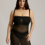 Woman wearing a black sheer dress against a plain background