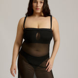 Woman wearing a black sheer dress against a plain background