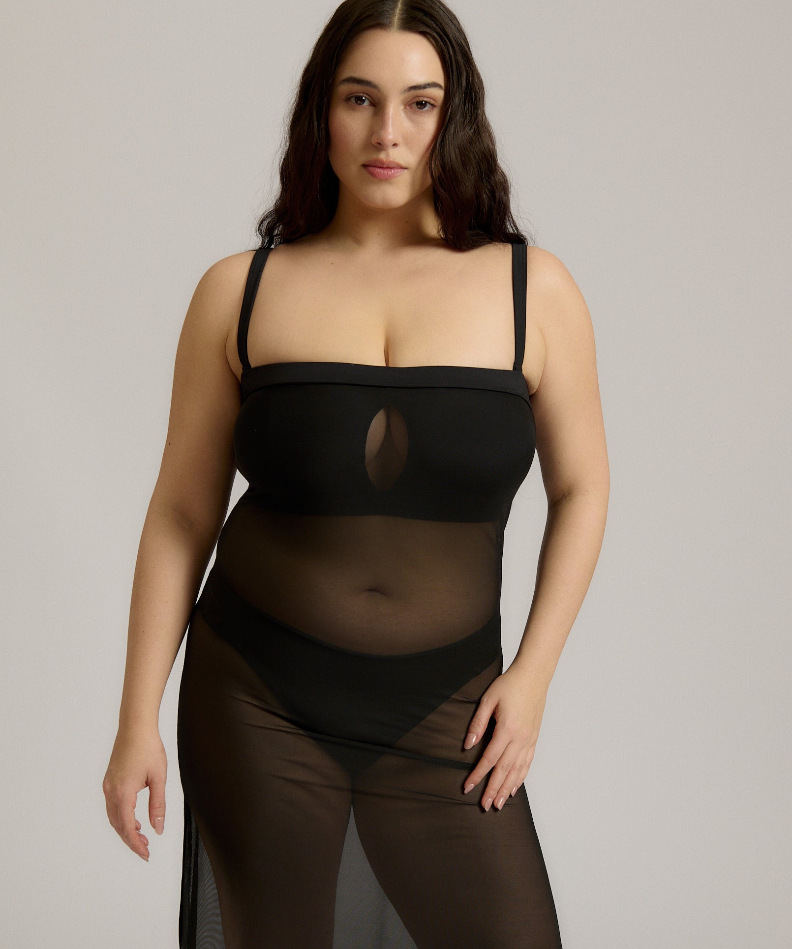 Woman wearing a black sheer dress against a plain background