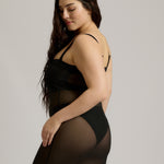 Woman wearing a black sheer dress against a plain background