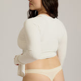 Woman wearing a white wrap top against a plain background