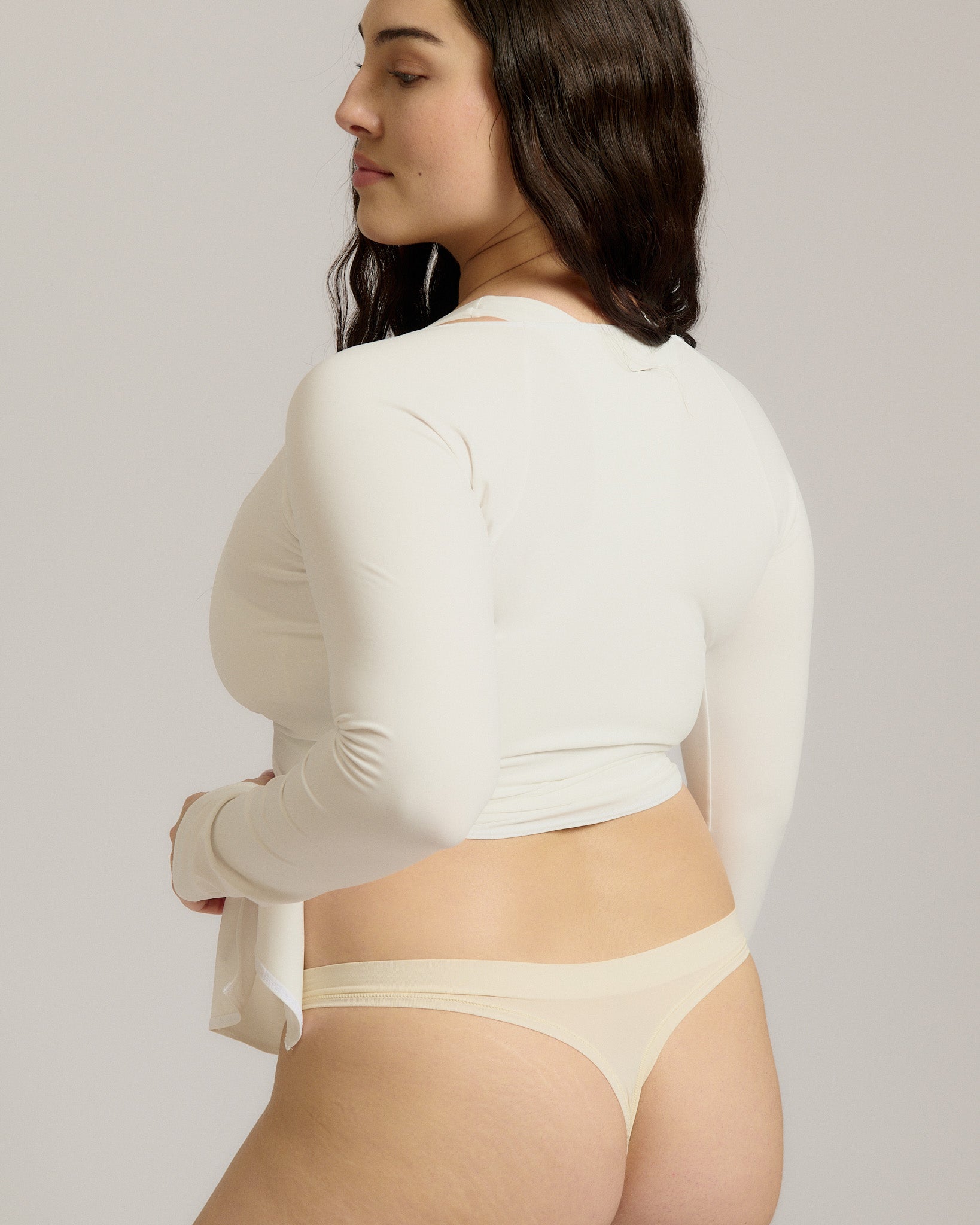 Woman wearing a white wrap top against a plain background