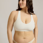 Woman wearing a white racerback on a plain background