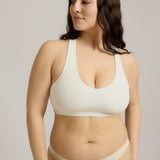 Woman wearing a white racerback on a plain background