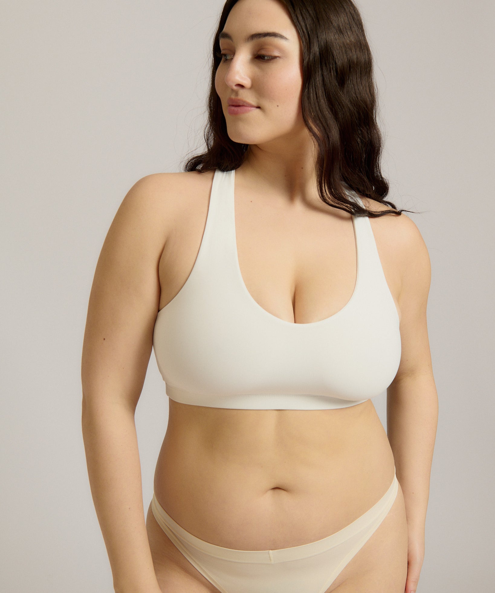 Woman wearing a white racerback on a plain background