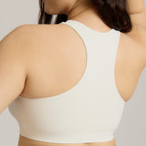 Woman wearing a white racerback on a plain background