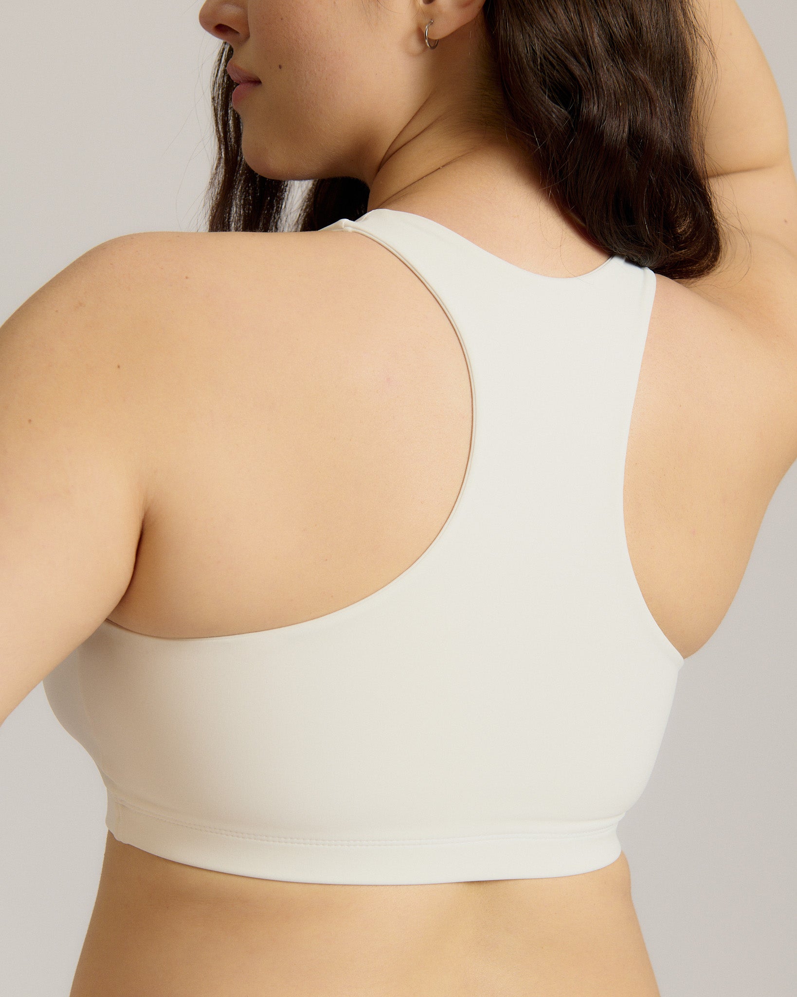 Woman wearing a white racerback on a plain background
