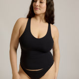 Woman wearing a black racerback against a plain background