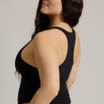 Woman wearing a black racerback against a plain background