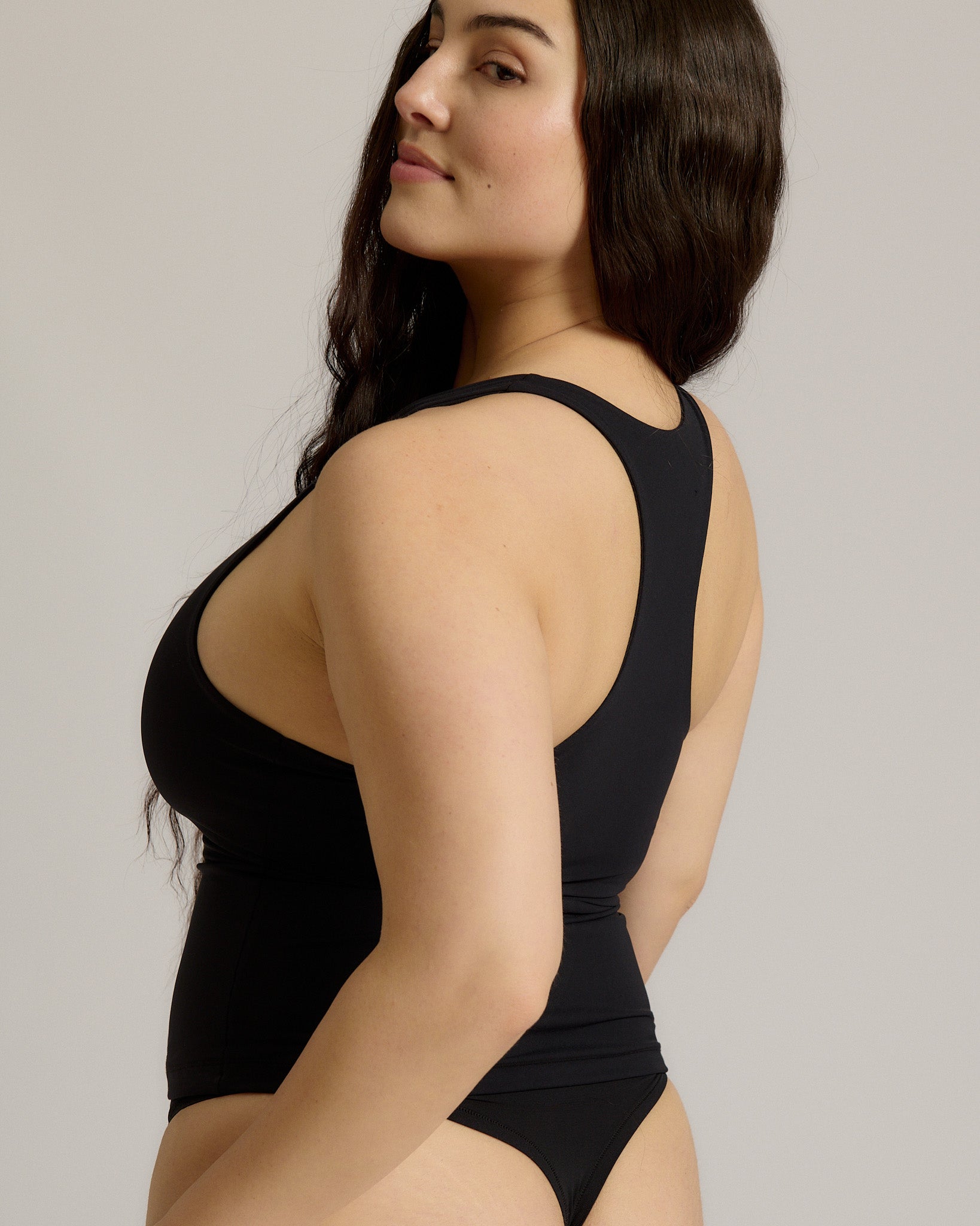 Woman wearing a black racerback against a plain background