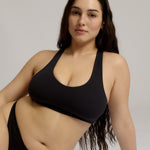 Woman wearing a black racerback on a plain background