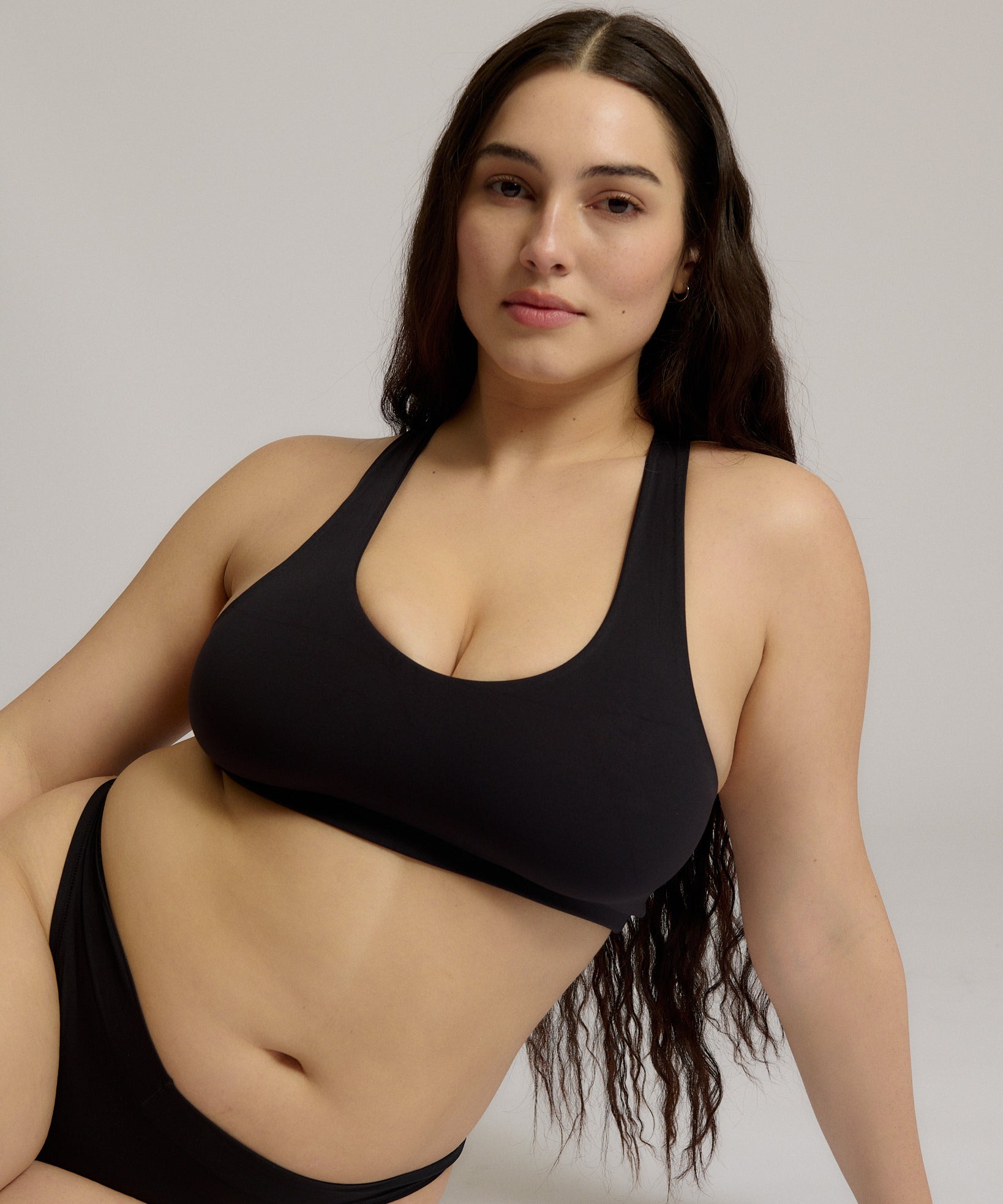 Woman wearing a black racerback on a plain background