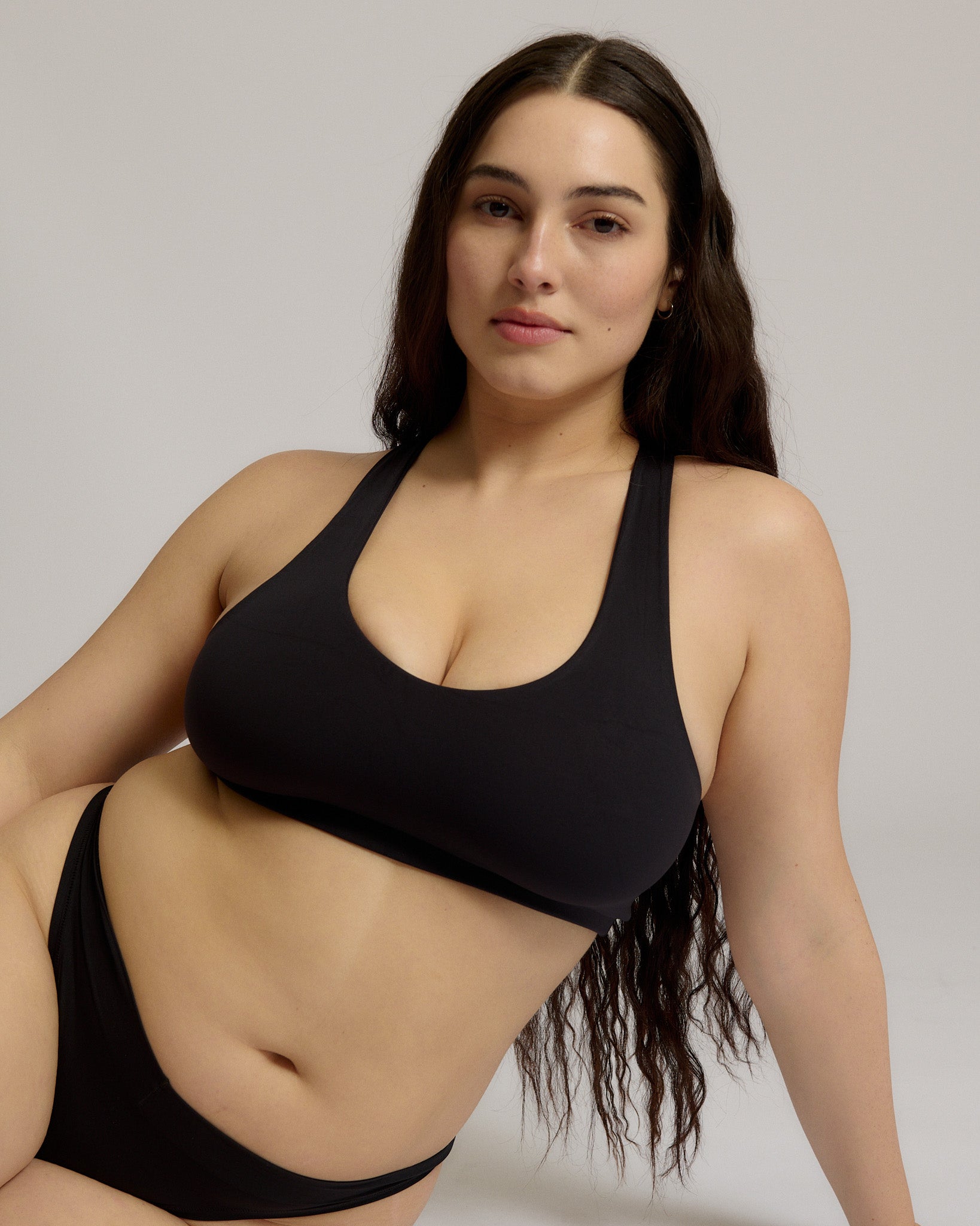 Woman wearing a black racerback on a plain background
