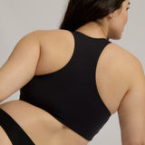 Woman wearing a black racerback on a plain background