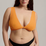 Woman wearing an orange nuudii on a plain background