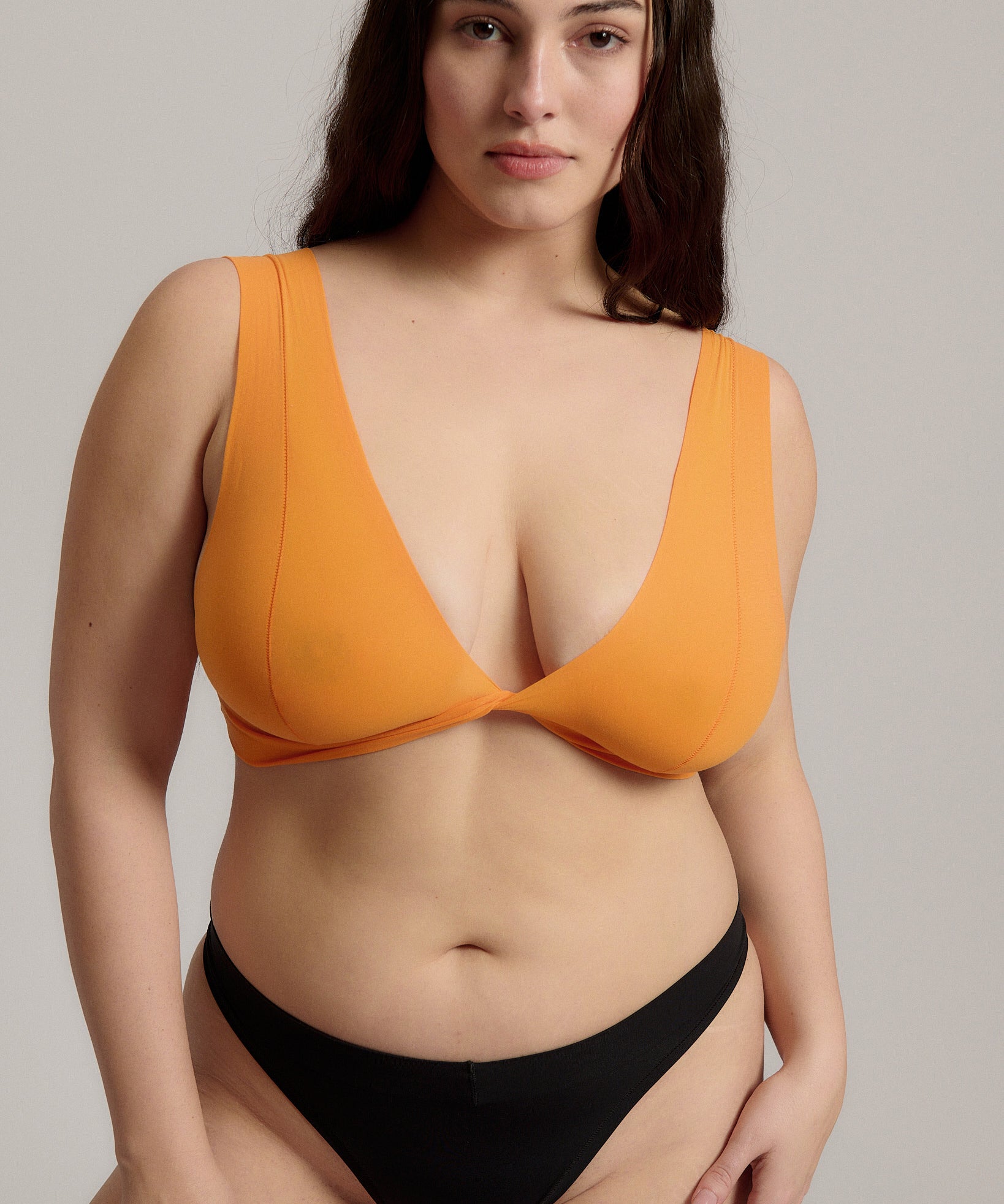 Woman wearing an orange nuudii on a plain background