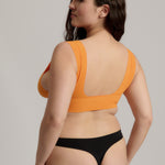 Woman wearing an orange nuudii on a plain background