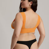 Woman wearing an orange nuudii on a plain background