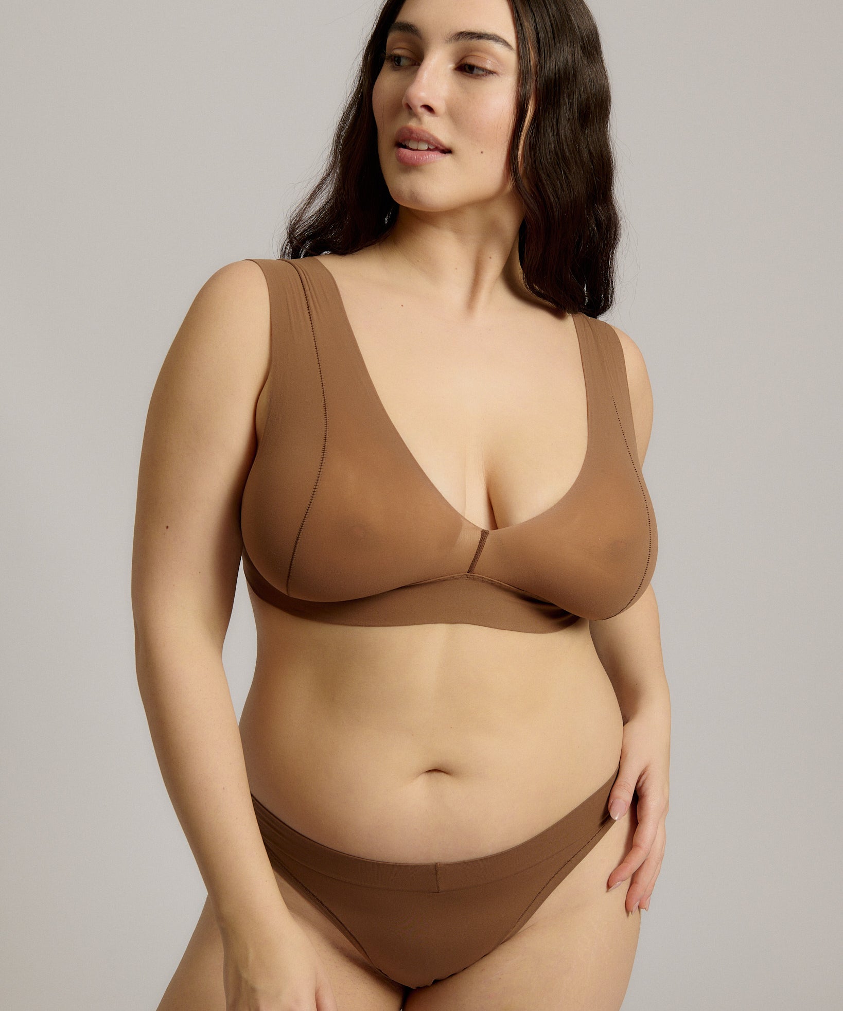 Woman wearing a brown bra against a plain background