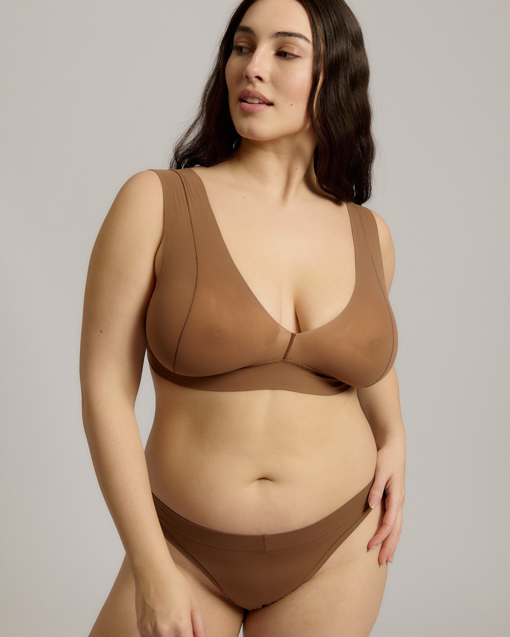 Woman wearing a brown bra against a plain background