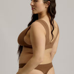 Woman wearing a brown bra against a plain background
