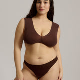 A woman wearing a brown Vii System bra, which is designed with a deep neckline, wide straps, and a smooth back.