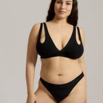 Woman wearing black tee system on plain background