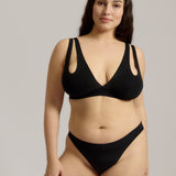 Woman wearing black tee system on plain background