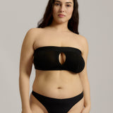 Woman wearing black strapless system against a neutral background