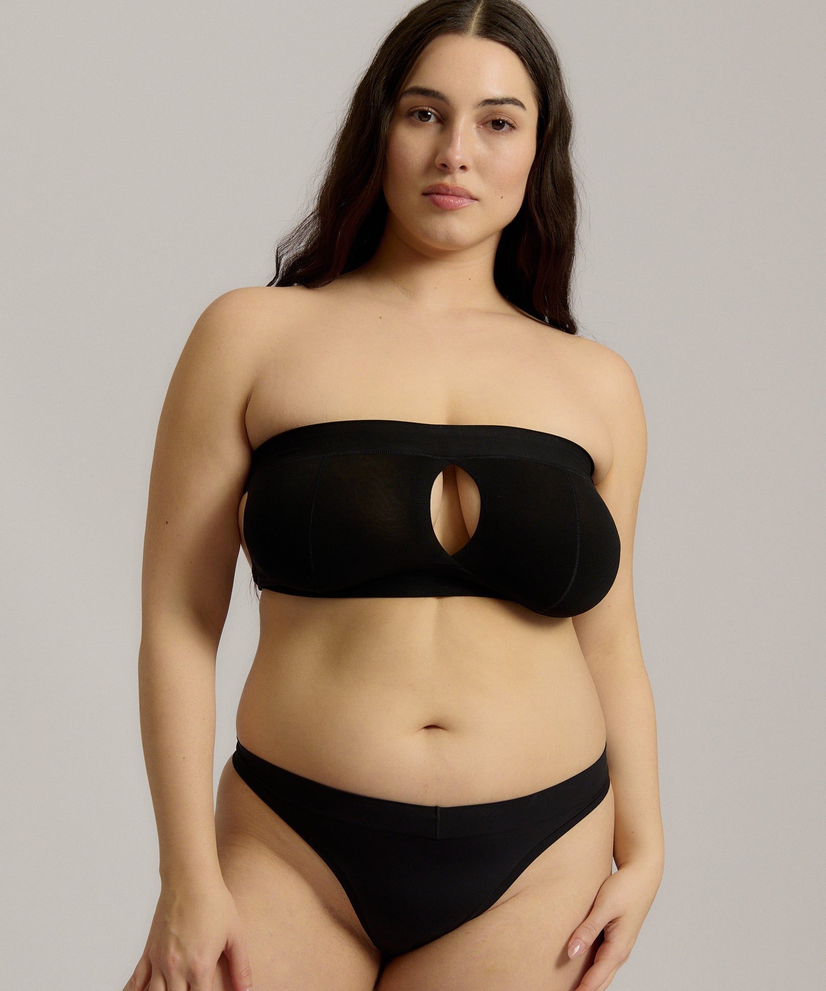 Woman wearing black strapless system against a neutral background