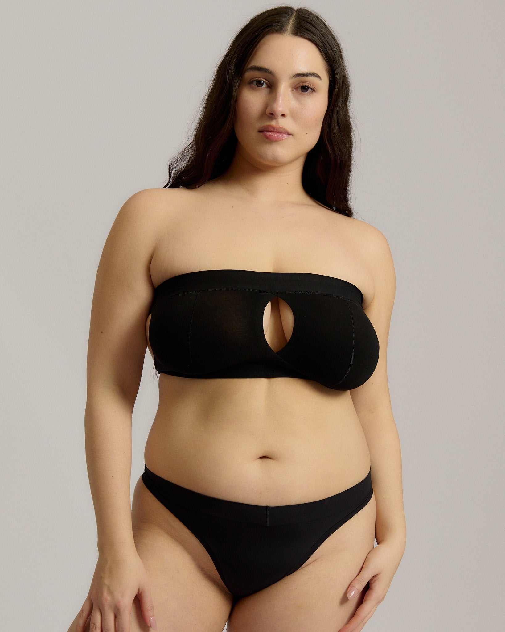 Woman wearing black strapless system against a neutral background