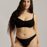 Person wearing a black cami system against a plain background