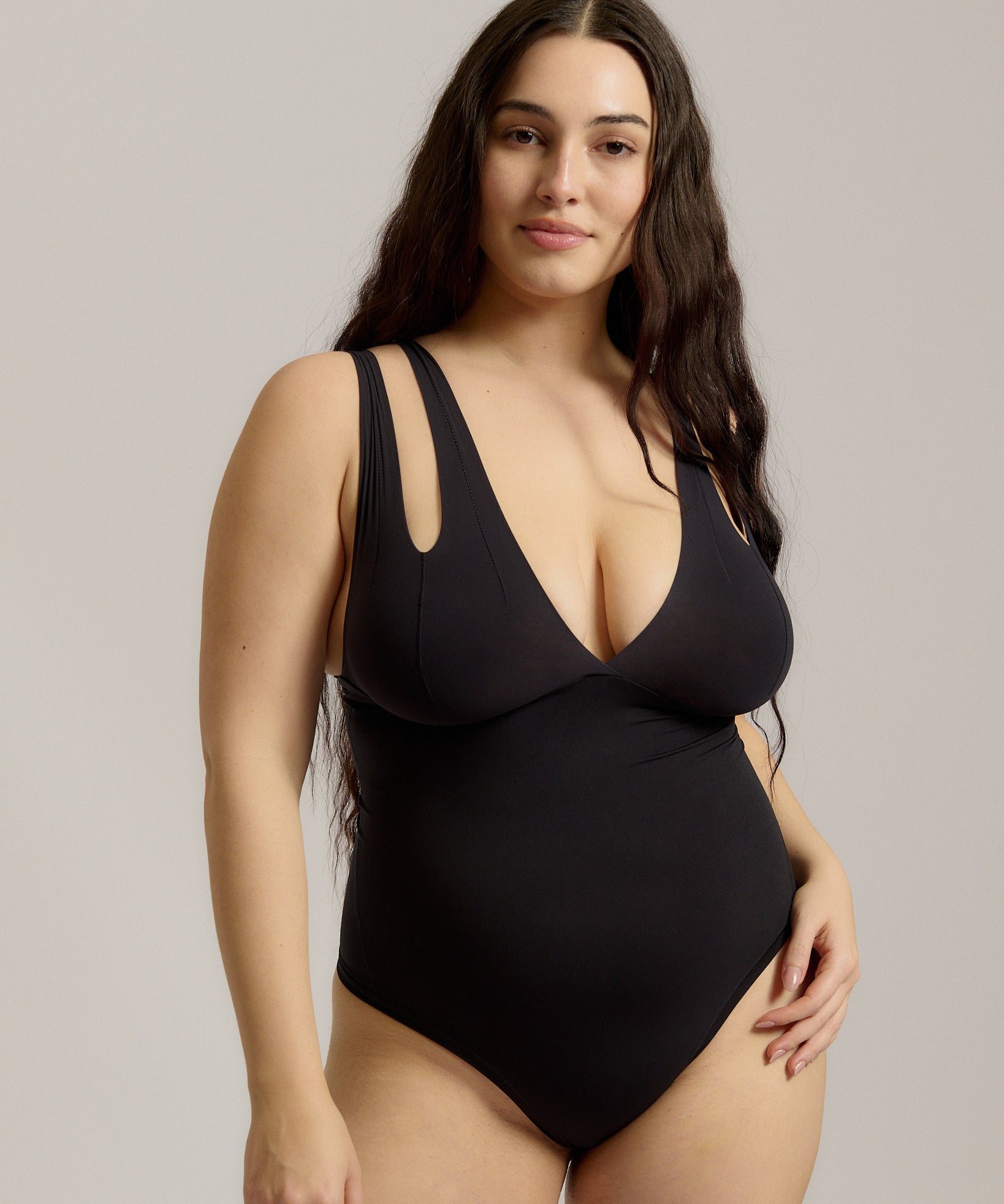 Woman wearing a black bodysuit against a plain background