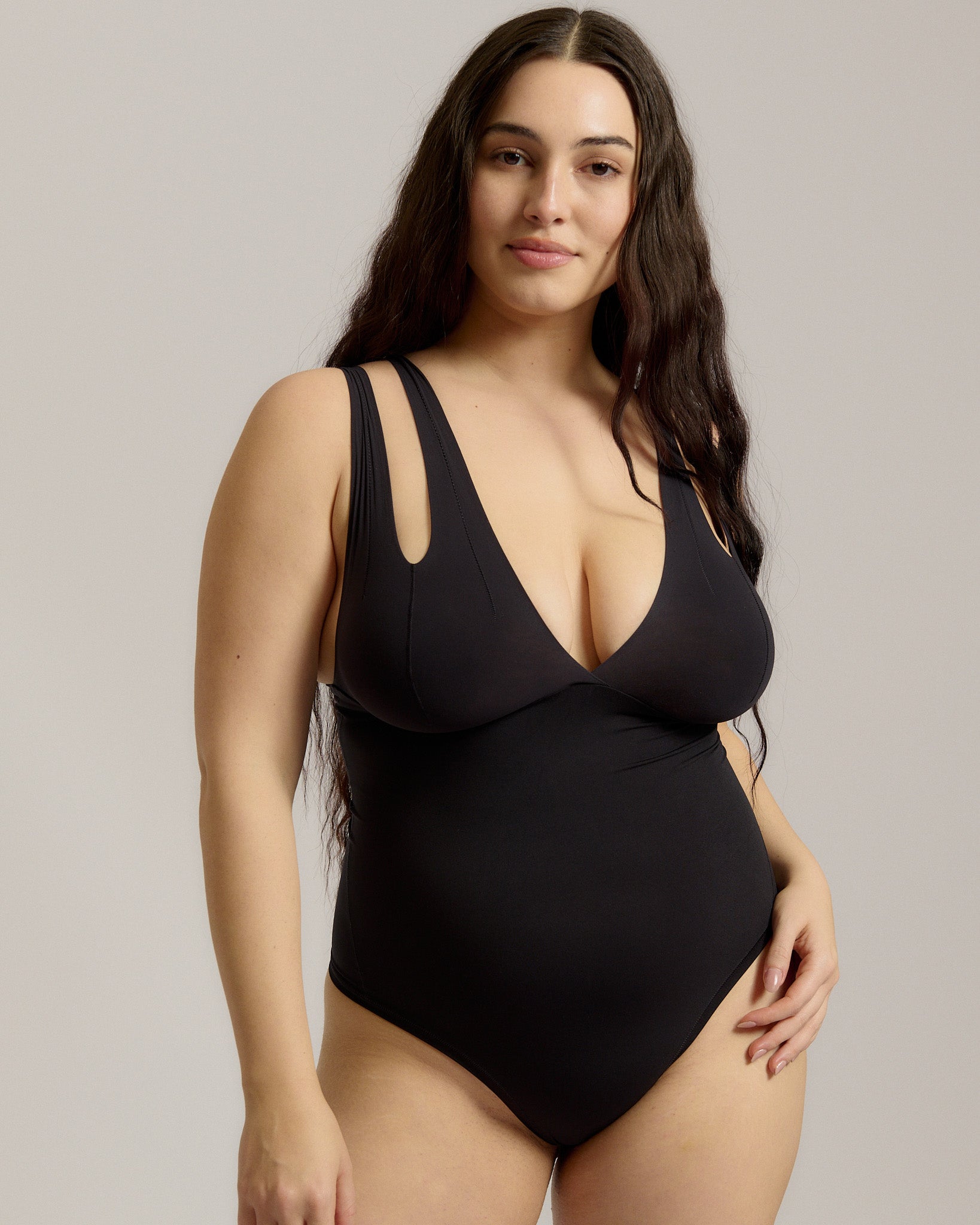 Woman wearing a black bodysuit against a plain background