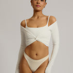 Woman wearing a white wrap top against a plain background