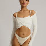 Woman wearing a white wrap top against a plain background