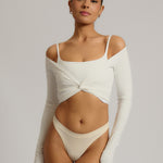 Woman wearing a white wrap top against a plain background