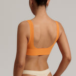 Woman wearing an orange nuudii on a plain background
