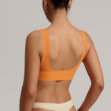 Woman wearing an orange nuudii on a plain background