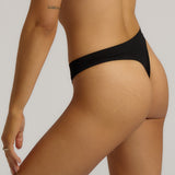 A woman wearing black thong underwear designed with a mid-rise cut.